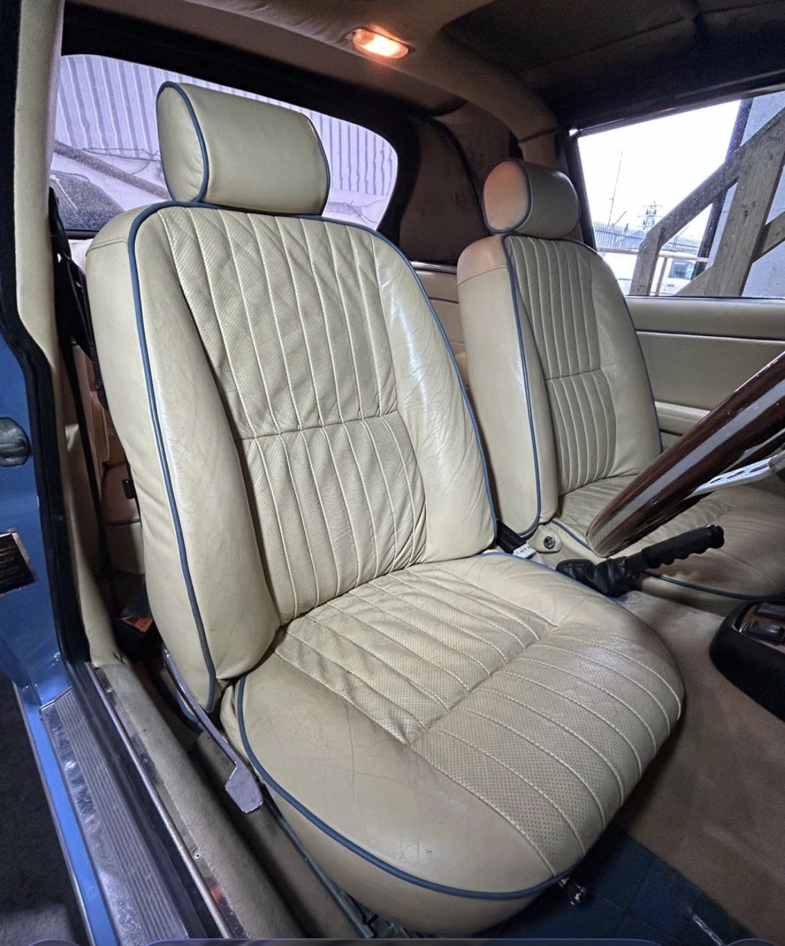 The front seats of KKH 295N back in the car, tan perforated leather with blue piping.