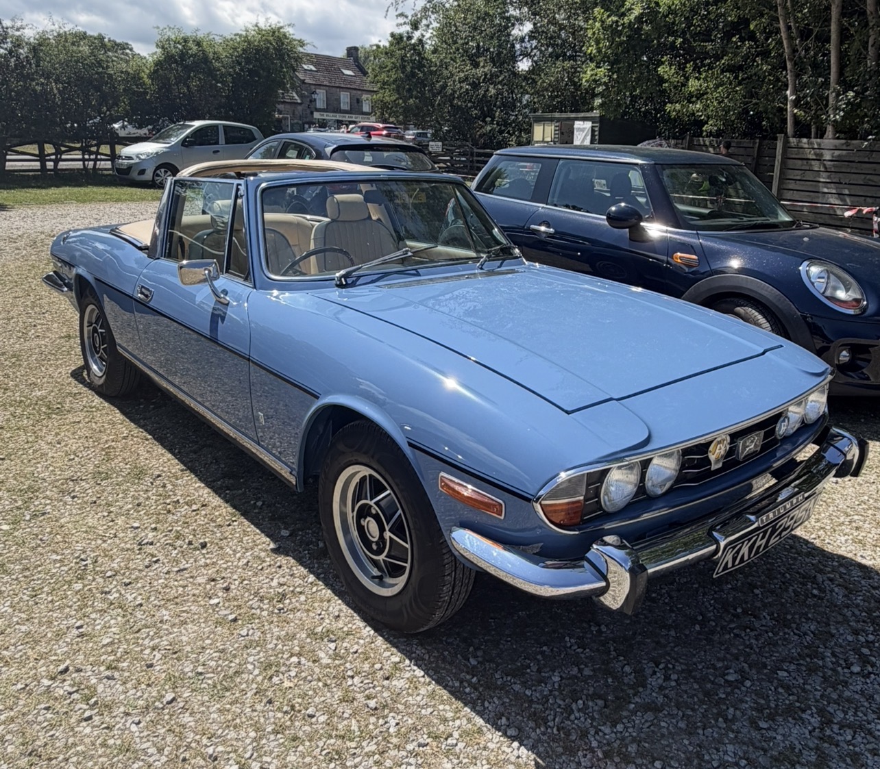 A French Blue Triumph Stag with the roof down, registration KKH 295N, parked on gravel at Goathland.