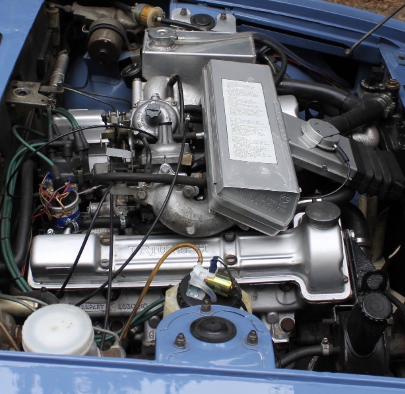 Triumph Stag engine bay showing the twin Zenith-Stromberg carburettors and throttle linkage.
