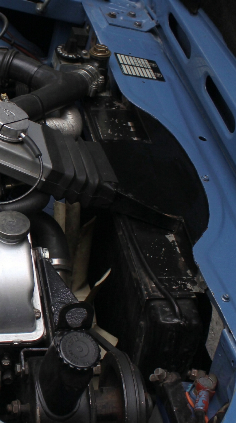 Triumph Stag electric cooling fan and thermostat switch installed in engine bay.