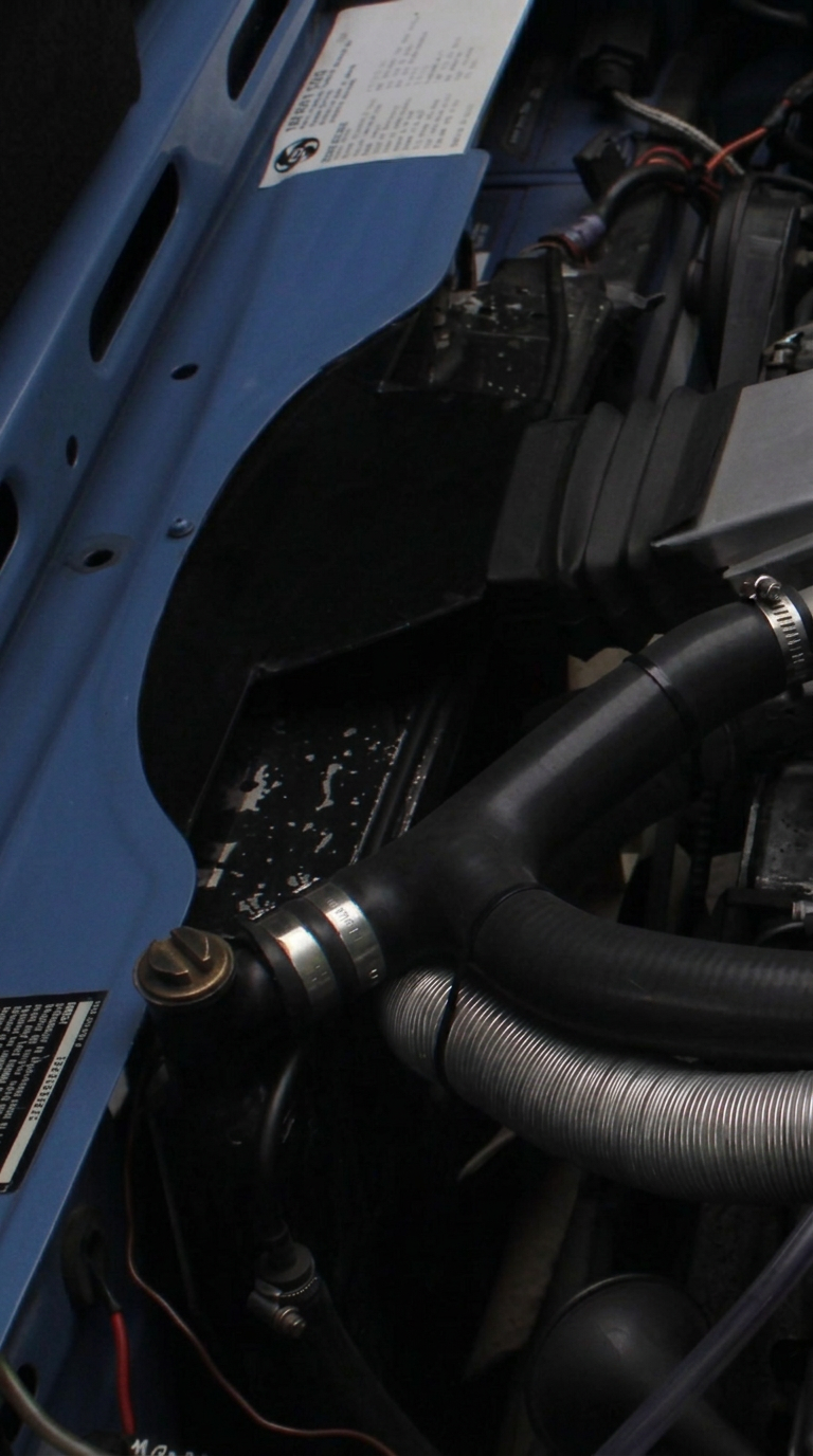 Triumph Stag engine bay showing uprated radiator with hose routing and electric fan boss.
